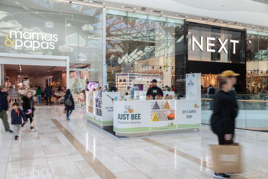 Man at Just Bee Rock Up and Pop Up kiosk merchandised with honey products